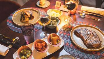 A dining table set with various dishes, including a steak, a bowl of soup, and a glass of wine.