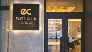 The entrance to the Elite Club Lounge with a marble wall and a sign.