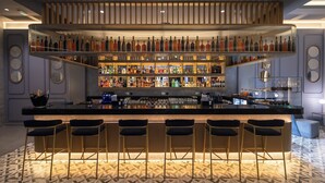 A bar area with multiple shelves of bottles, bar stools, and a patterned floor.