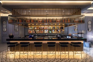 A bar area with multiple shelves of bottles, bar stools, and a patterned floor.