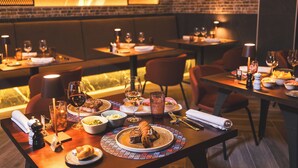 Un restaurant amb taules preparades per dinar, que mostra plats, gots i coberts.