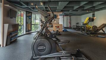 A gym with a stationary bike, weight bench, and exercise equipment.