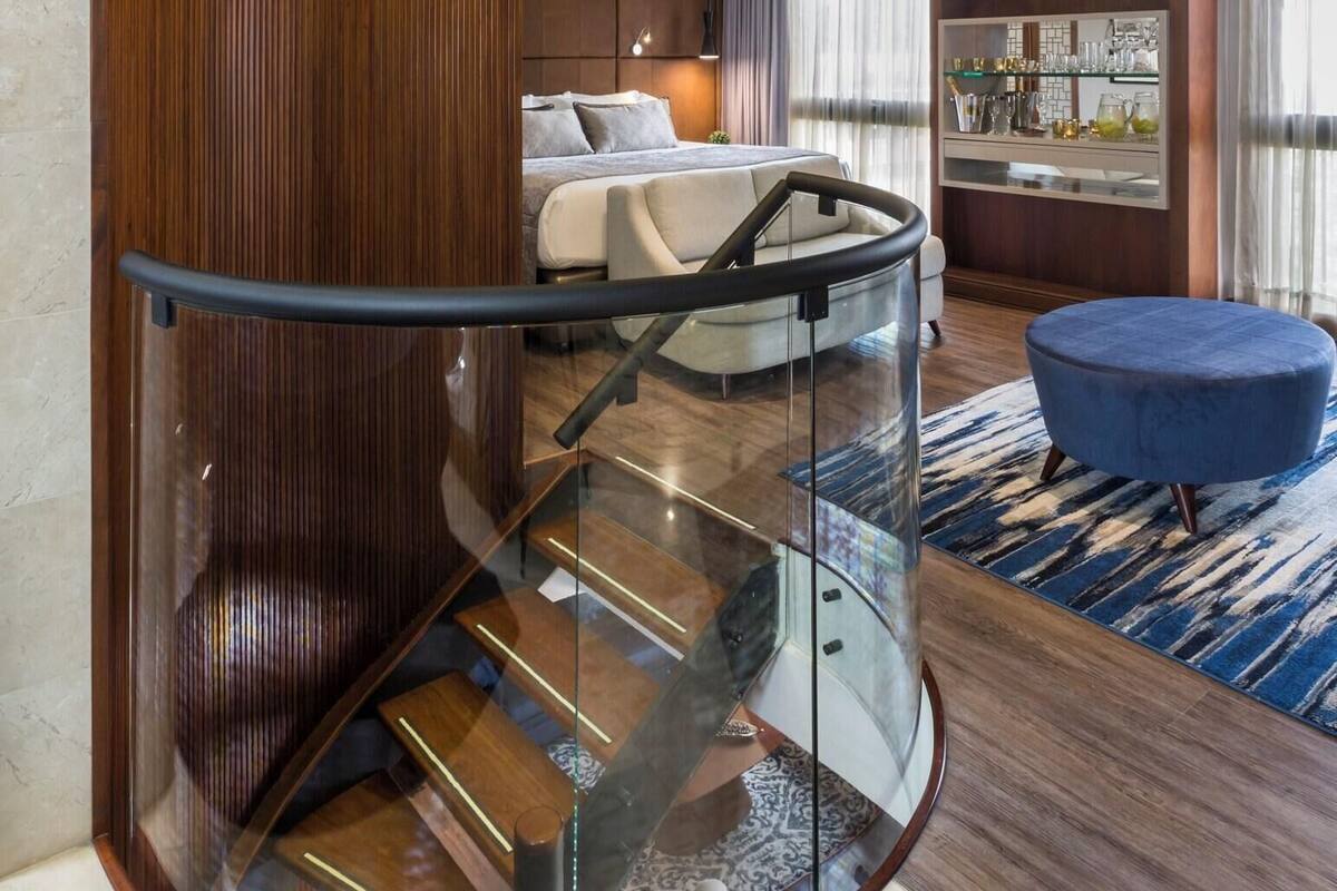 Una habitación de hotel moderna con una escalera curva, una cama, una zona de estar y un bar.