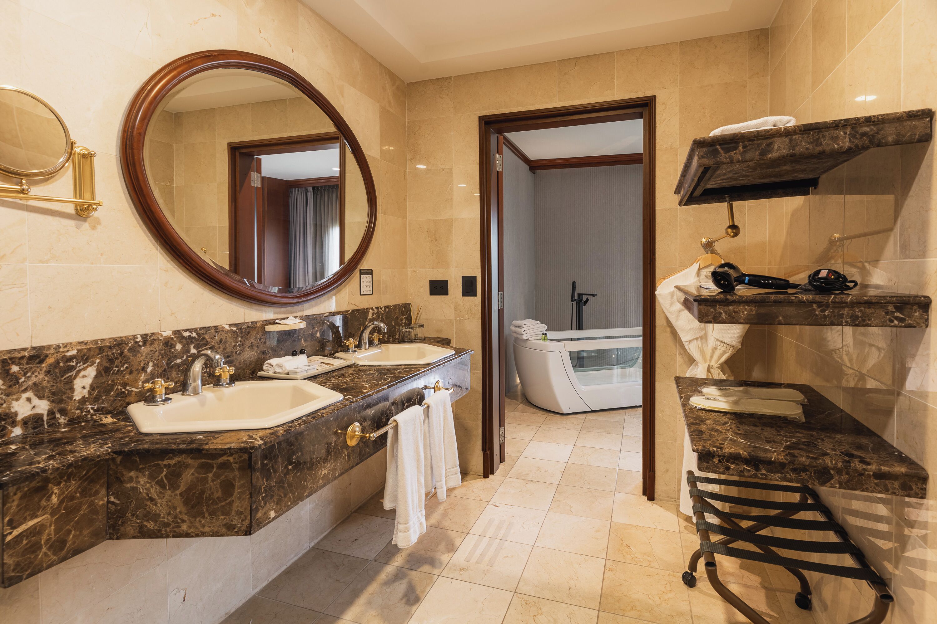 Une salle de bain moderne avec deux vasques, un grand miroir, une baignoire et un meuble-lavabo doté d’un porte-serviettes.