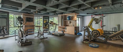A gym with exercise equipment, large windows, and a high ceiling.