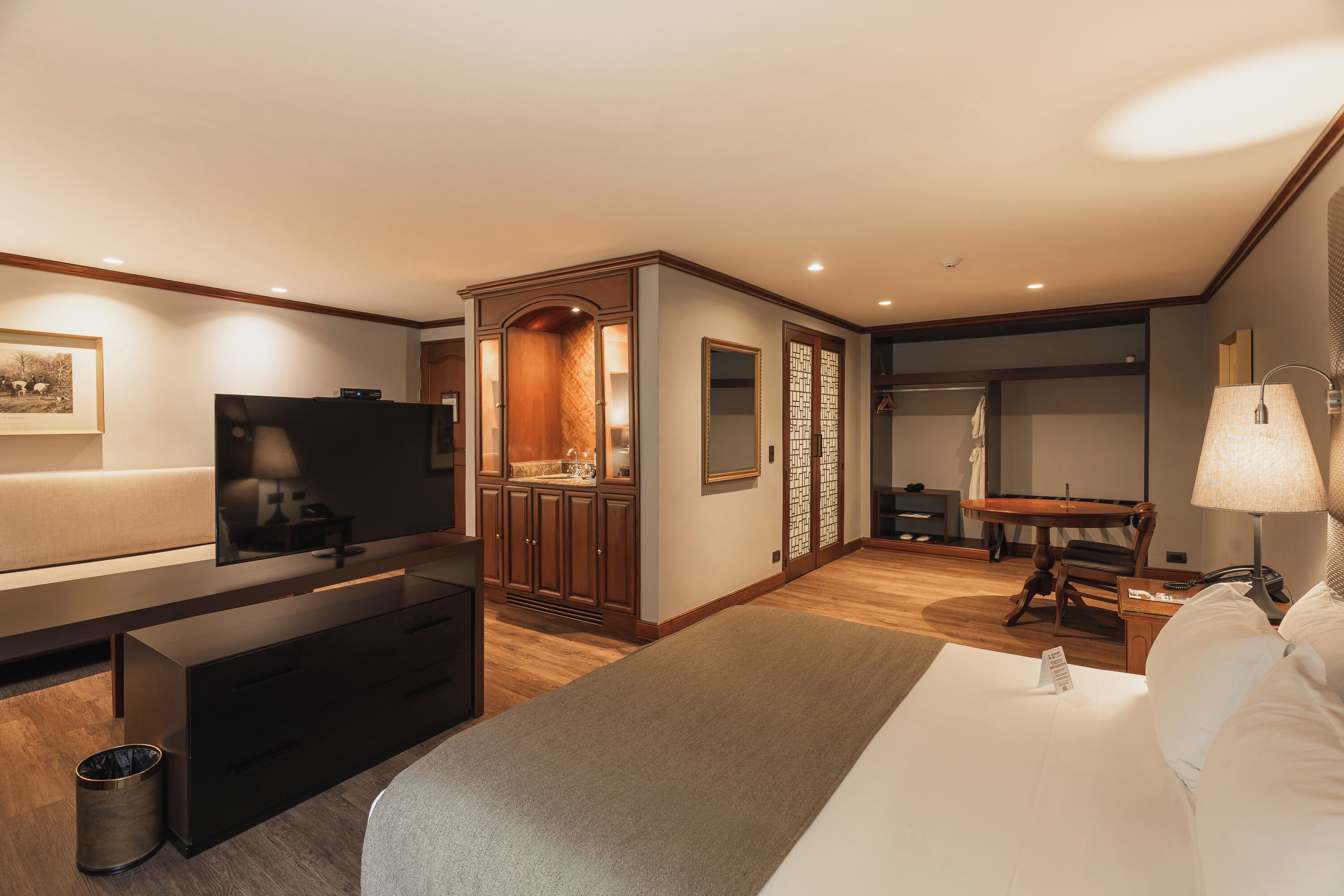 Ein Hotelzimmer mit Bett, Fernseher, Schreibtisch und Bad.