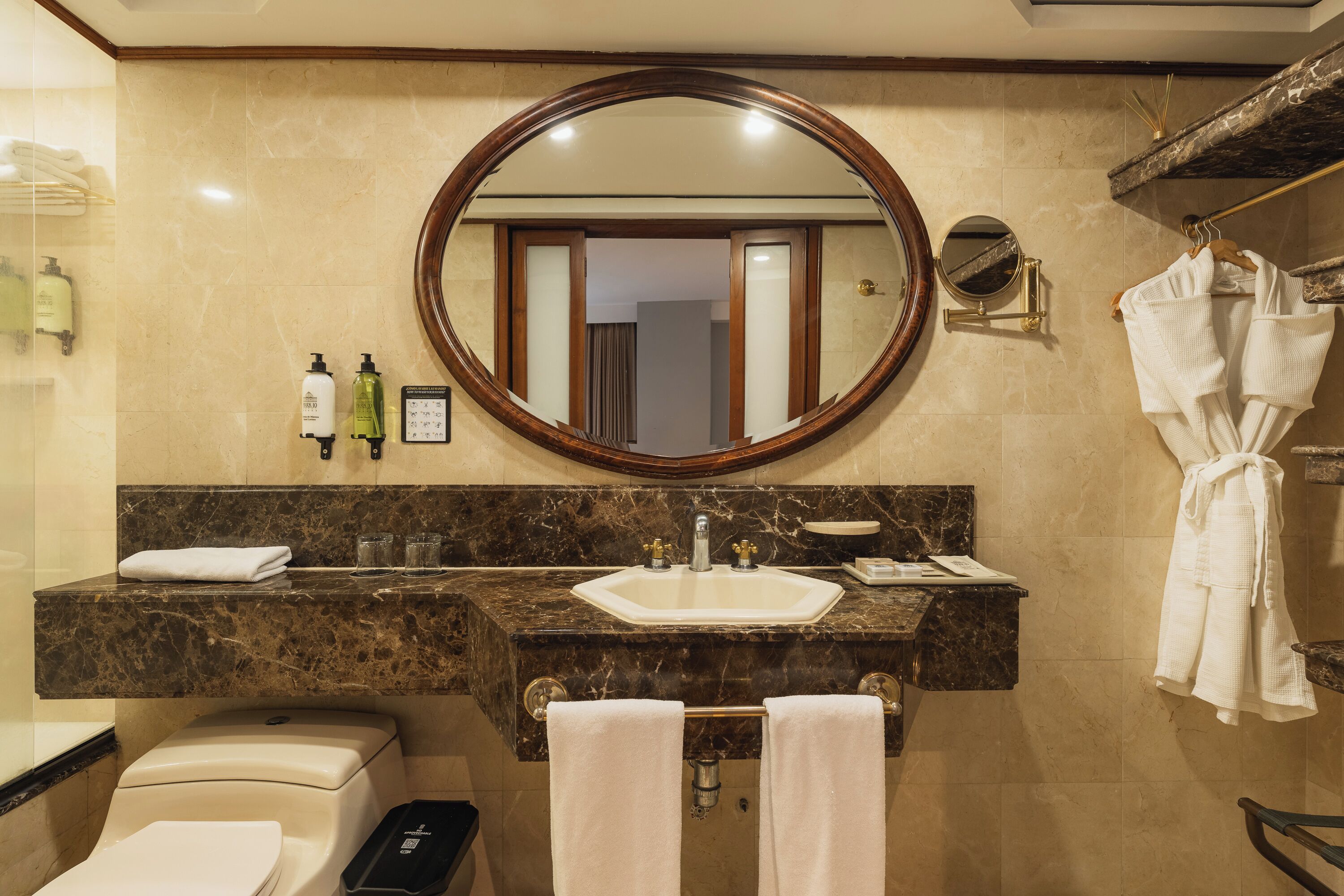 A bathroom with a marble sink, a large mirror, and a towel rack.
