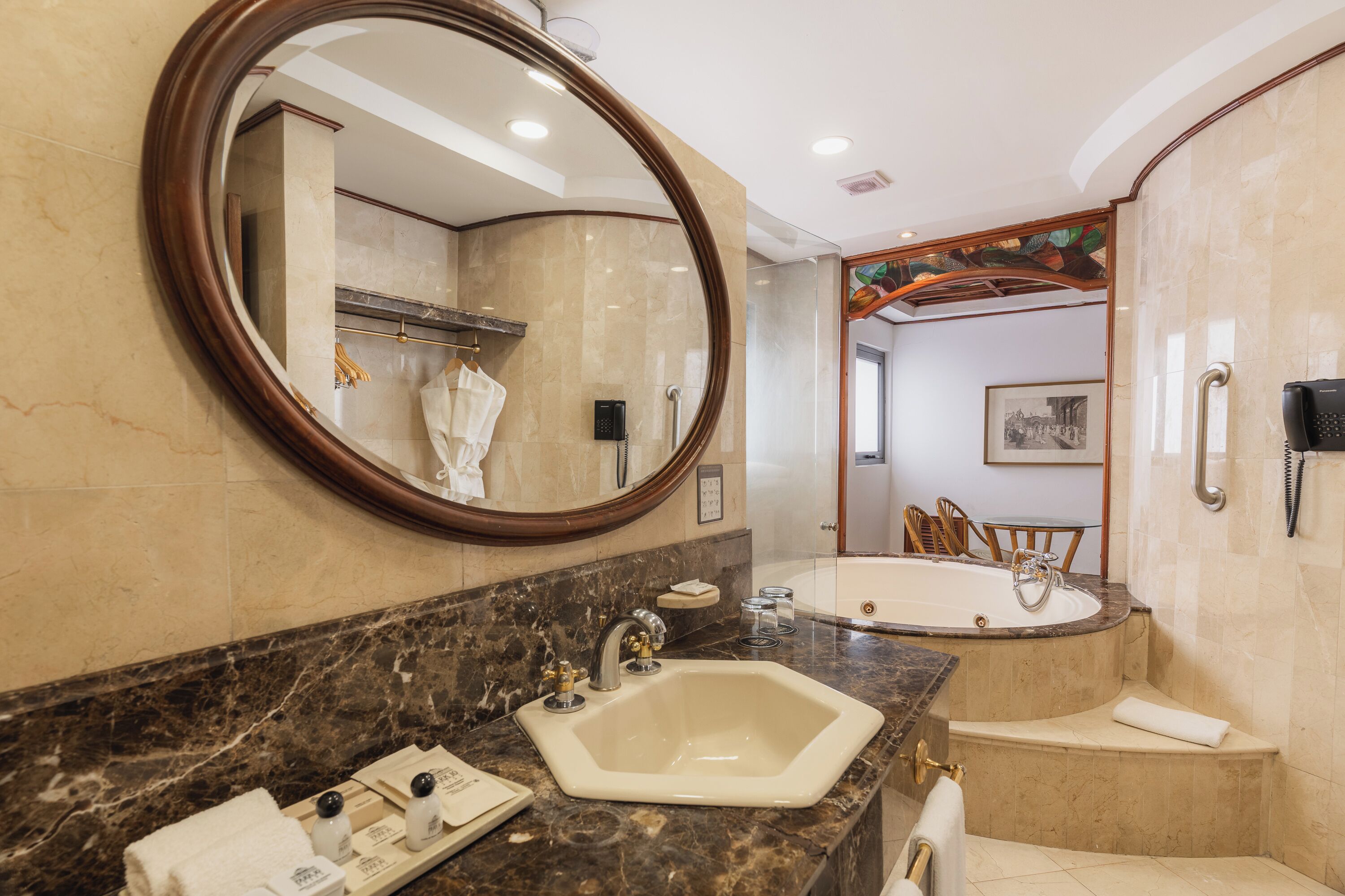 A bathroom with a marble sink, a large mirror, a bathtub, and a shower area.