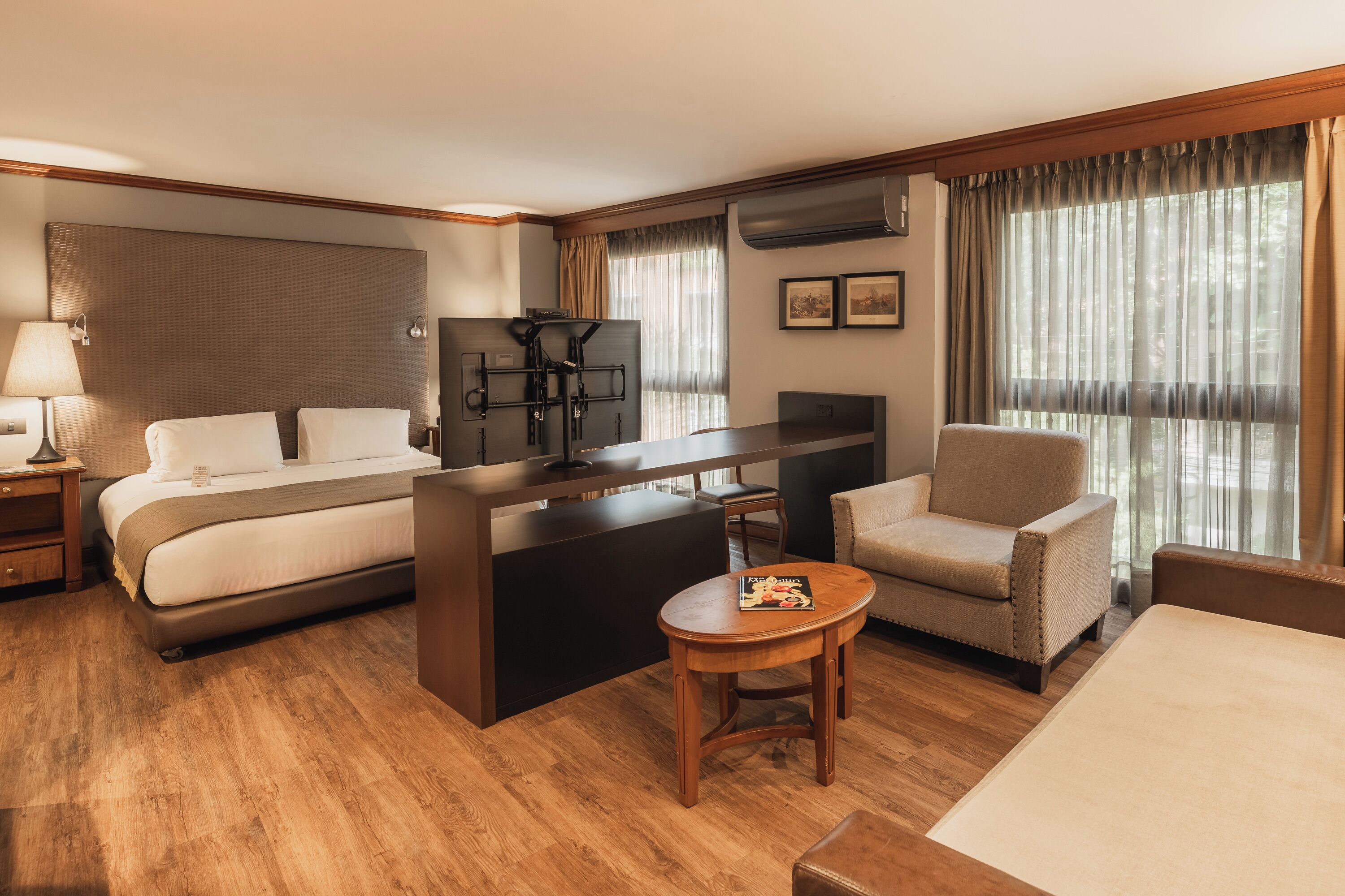 Una habitación de hotel con cama, escritorio, silla, mesita y televisión.