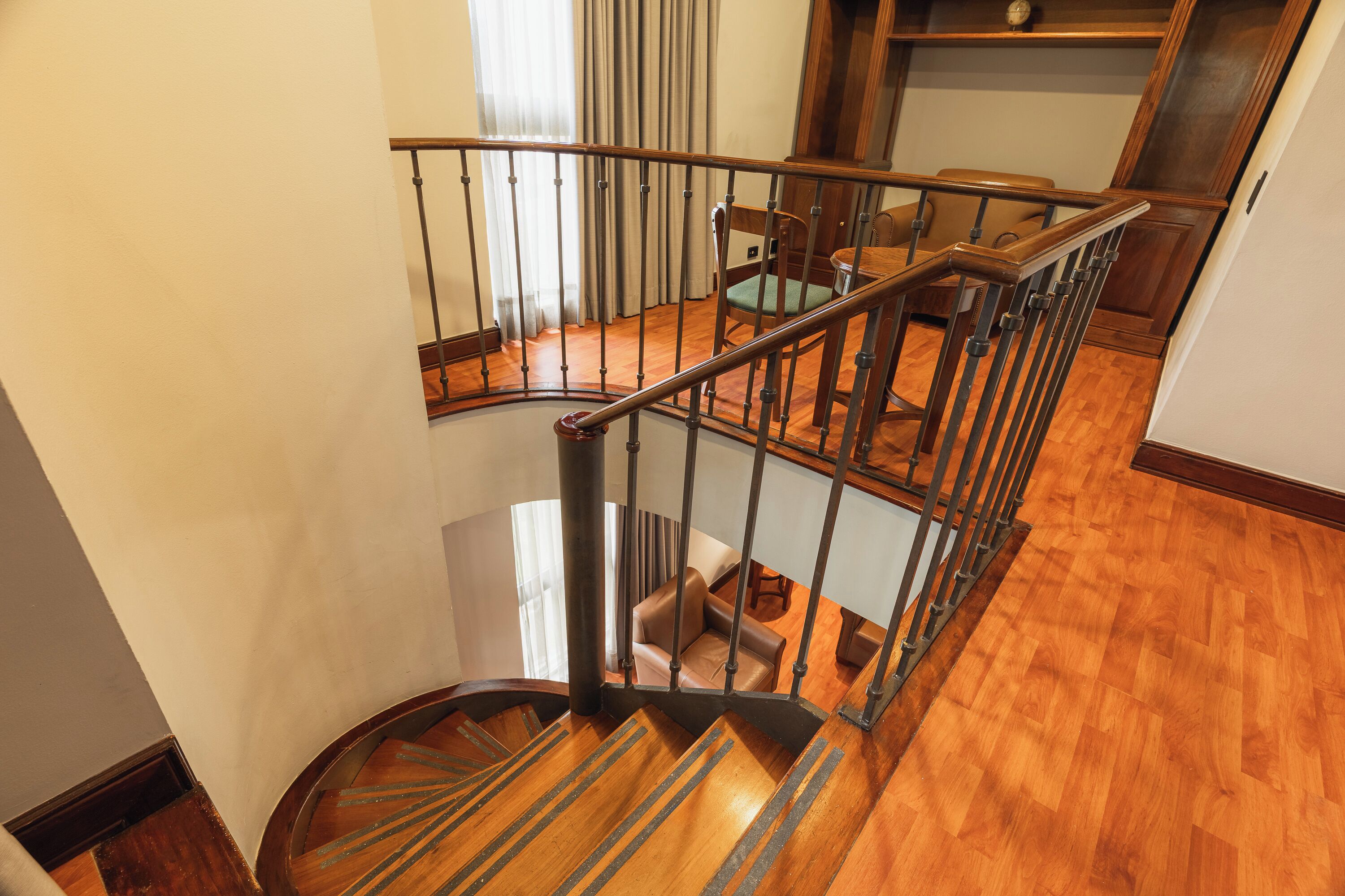 A wooden staircase with a metal railing, a leather sofa, and a wooden floor.