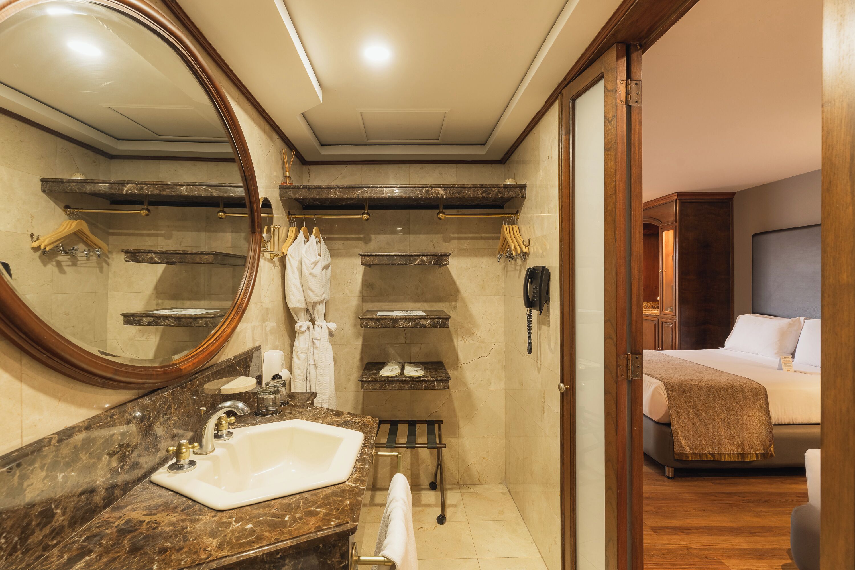A bathroom with a marble sink, a large mirror, towel racks, and a shower area.