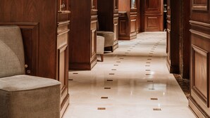 A hallway with wooden paneling, a chair, and a polished marble floor.