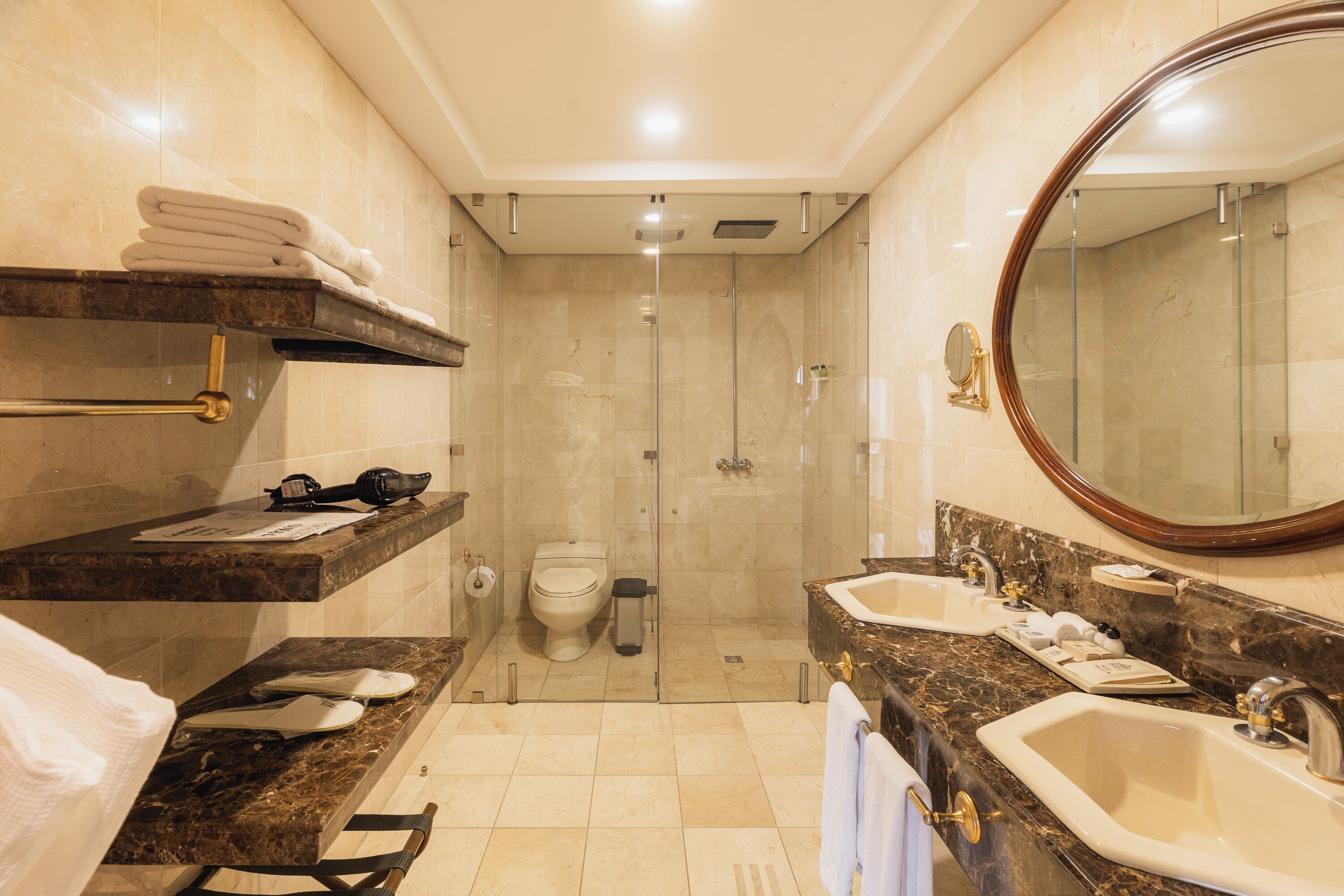 Un baño con ducha, inodoro, lavamanos y perchero para toallas.