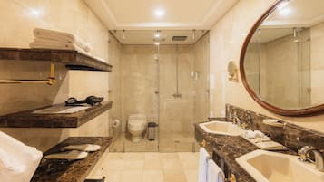 Un baño con ducha, inodoro, lavamanos y perchero para toallas.