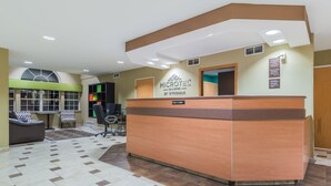 A reception area with a reception desk, seating area, and a large window. - Microtel Inn & Suites by Wyndham West Chester (West Chester)