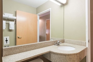 Une salle de bain avec un comptoir en granit, un lavabo, un miroir et un porte-serviettes.