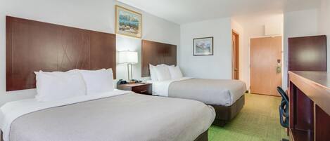 A hotel room with two beds, a desk, and a chair.