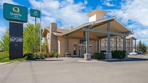 Entrada del hotel Quality Inn, con un área de espera cubierta y un pilar de piedra.