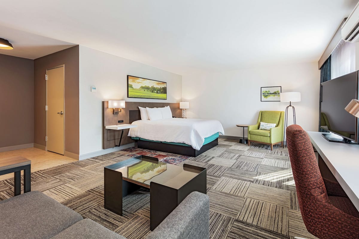A hotel room with a bed, a desk, a chair, and a small table.