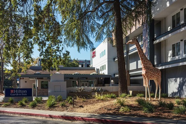 Un Hilton Garden Inn con una estatua grande de jirafa en su fachada.