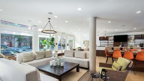 A modern hotel lobby with a seating area, a bar, and a view of the street. - Hilton Garden Inn Davis Downtown (Davis)