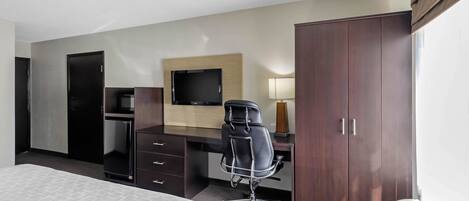 Ein Hotelzimmer mit Bett, Schreibtisch, Stuhl, Fernseher, Kleiderschrank und Heizung.