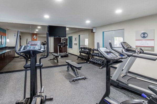 A gym with treadmills, dumbbells, and a bench.