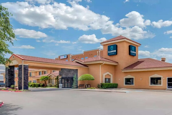 A hotel with a prominent 'Clarion' sign, a red-tiled roof, and a landscaped entrance area.