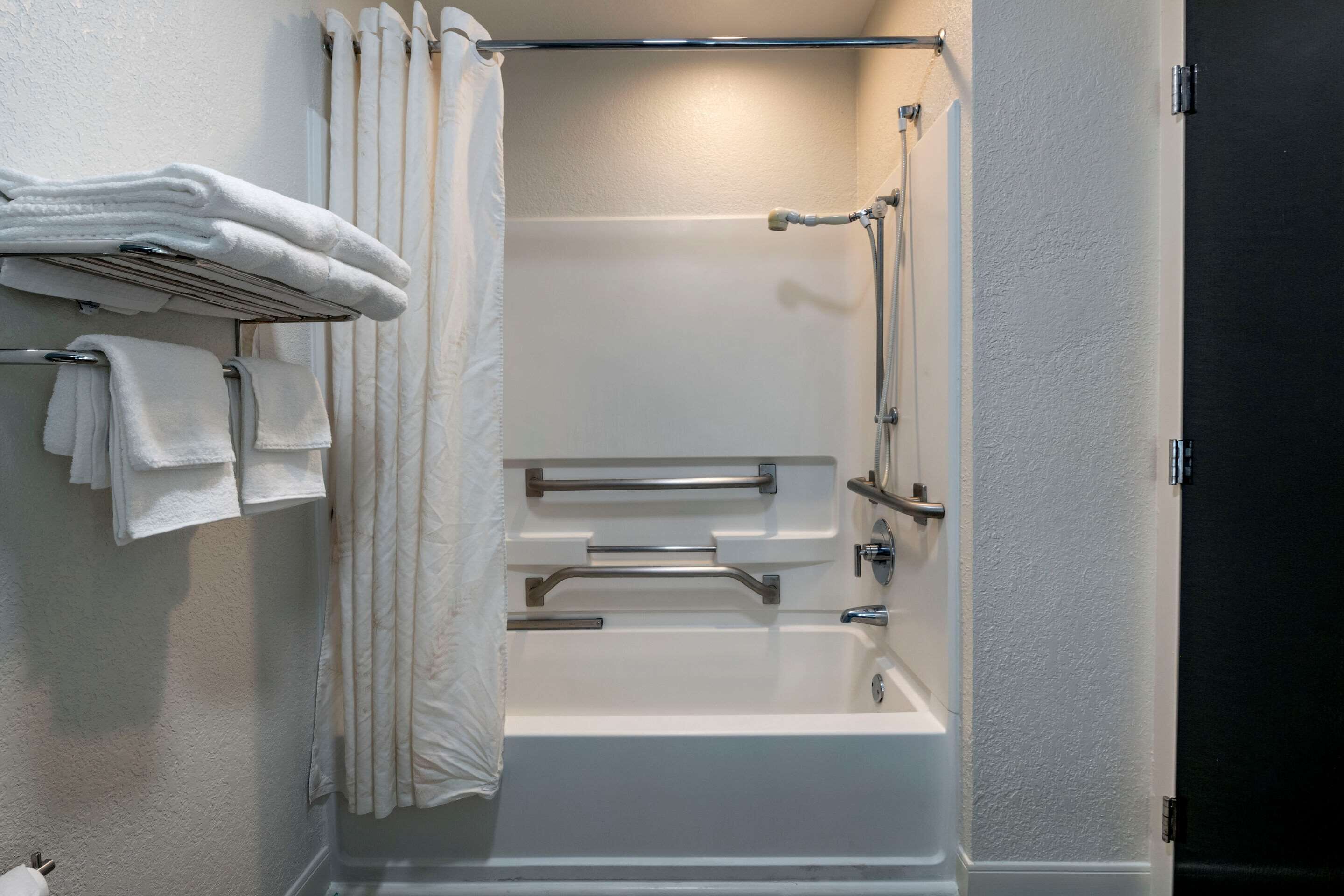 Un baño moderno con una bañera, zona de ducha y un perchero con toallas dobladas.