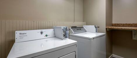 A laundry area with two Whirlpool front-loading washers and a countertop with a sink.