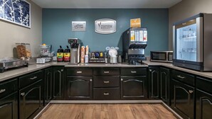 A modern kitchen with dark cabinetry, a coffee station, and a refrigerator. - Sleep Inn Jacksonville Airport (Jacksonville)