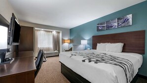 A hotel room with a bed, a desk, a television, a lamp, and a window with curtains. - Sleep Inn Jacksonville Airport (Jacksonville)