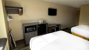 A hotel room with two beds, a desk with a microwave, a TV, and a coat rack.