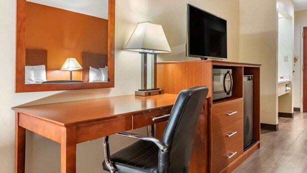 A hotel room with a wooden desk, a black leather chair, a flat-screen TV, a lamp, and a microwave. - Econo Lodge Saint Stephen (St. Stephen)