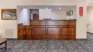 A reception desk with a wooden finish, a framed picture on the wall, and a red sign with recycling symbols. - Econo Lodge Saint Stephen (St. Stephen)