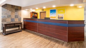 A reception desk with a wooden finish, a clock, and a 'Hello Sunshine' sign. - Days Inn & Suites by Wyndham Greeley (Greeley)