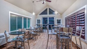 A spacious dining area with multiple tables and chairs, large windows, and a ceiling fan. - Days Inn & Suites by Wyndham Greeley (Greeley)