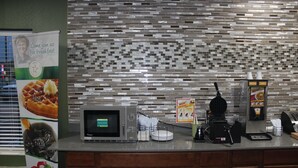 A breakfast counter with a waffle maker, coffee machine, and a menu board. - Quality Inn North Vernon near Hwy 50 (North Vernon)