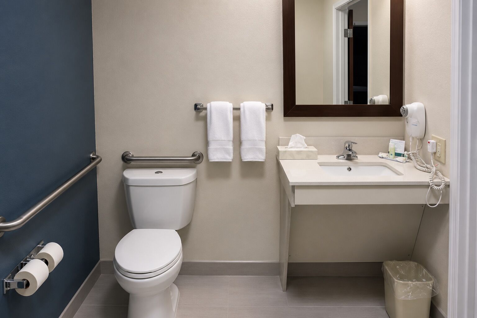 A standard hotel bathroom with a toilet, bidet, sink, and mirror.