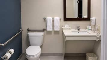 A standard hotel bathroom with a toilet, bidet, sink, and mirror.