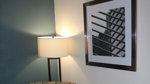 A chair with a circular pattern, a lamp, and a framed picture on the wall. - Quality Inn North Vernon near Hwy 50 (North Vernon)