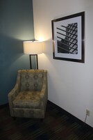 Una silla con un diseño circular, una lámpara y un cuadro en la pared.