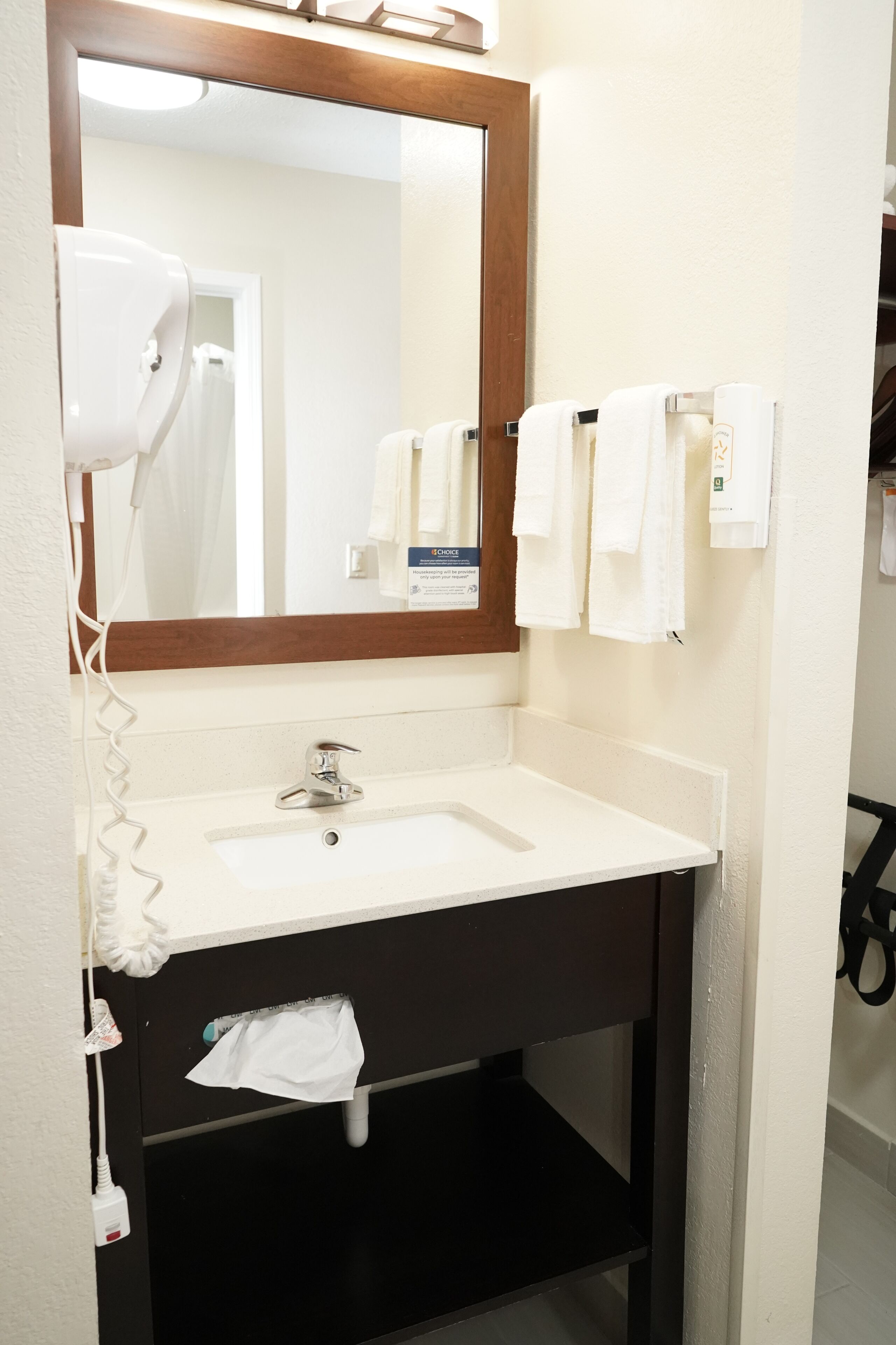 A bathroom with a white sink, a mirror, a hairdryer, and a towel rack with towels.
