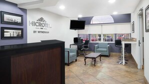 A reception area with a counter, seating, a TV, and a window with a view. - Microtel Inn by Wyndham Bowling Green (Bowling Green)