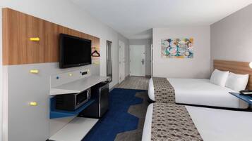 A hotel room with a bed, a TV, a desk, and a wall-mounted TV.