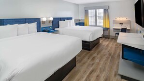 A hotel room with two beds, a desk, a chair, a TV, and a window with curtains. - Microtel Inn by Wyndham Athens (Athens)