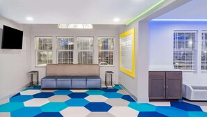 A modern waiting area with a blue and white hexagonal patterned floor, a grey sofa, and a small cabinet. - Microtel Inn by Wyndham Athens (Athens)