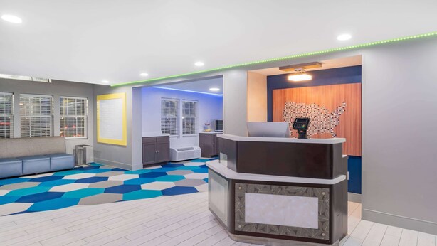 A reception area with a check-in counter, a seating area with a sofa, and a patterned floor. - Microtel Inn by Wyndham Athens (Athens)