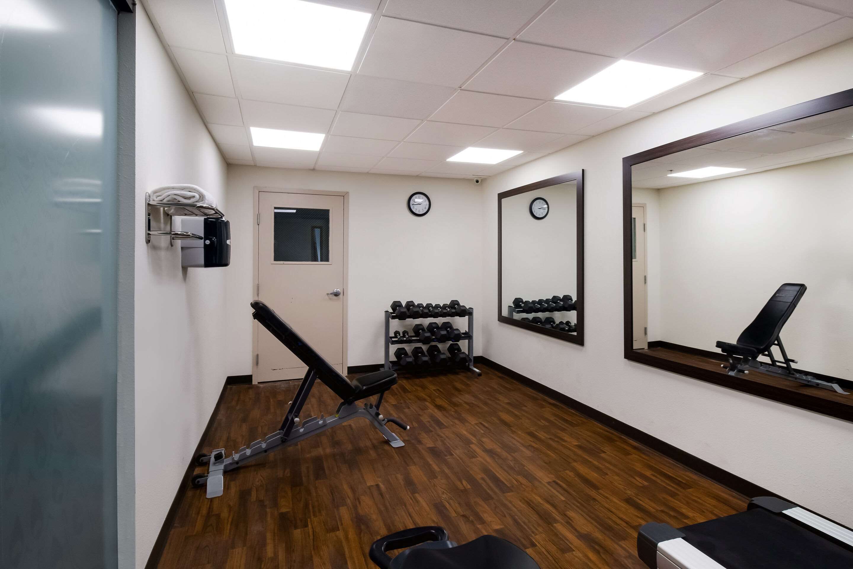 A gym with exercise equipment, a mirror, and a door.