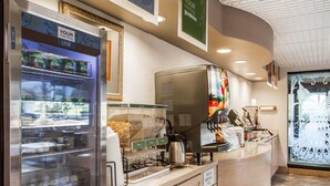 A self-service breakfast area with a refrigerated display case, coffee machines, and a trash bin. - Quality Inn Columbia I-65 (Columbia)